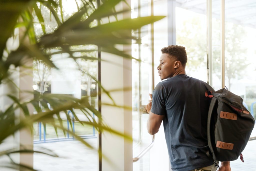 How Can A Young Adult Start Building Good Credit? man holding glass door